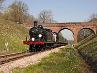 Steam engine pulling a passenger train and passing bridge on the
